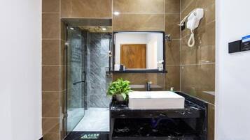 Un baño moderno con cabina de ducha de vidrio, lavamanos de mármol y una planta en maceta.