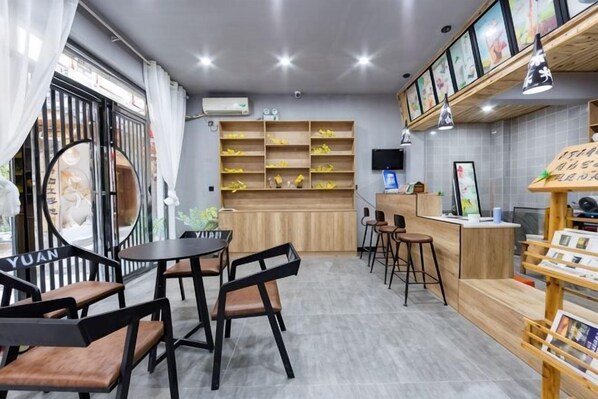 A restaurant with a counter, chairs, tables, and shelves with items. - Phoenix kinship light luxury B & B (Fenghuang County)
