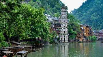 A traditional building with a multi-tiered pagoda-style roof, situated beside a river with boats.