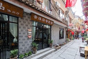 A traditional building with a signboard, potted plants, and a tiled pavement.