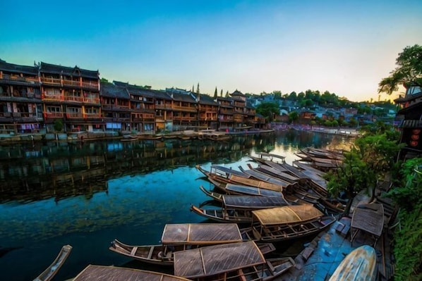 A riverside view with traditional buildings and wooden boats docked along the water.