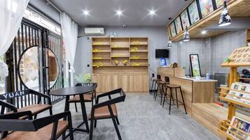A cafe with a wooden counter, bar stools, and a display of books and magazines.
