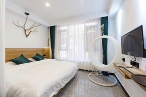 A modern hotel room with a large bed, a television, a circular light fixture, and a view of the outdoors. - Phoenix kinship light luxury B & B (Fenghuang County)