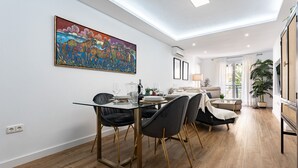 Un comedor moderno con una mesa de vidrio, sillas negras y un cuadro abstracto colorido en la pared.