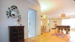 Un ampio soggiorno con pavimento in parquet in legno, un tavolo da biliardo, un divano e uno specchio decorativo con edera.