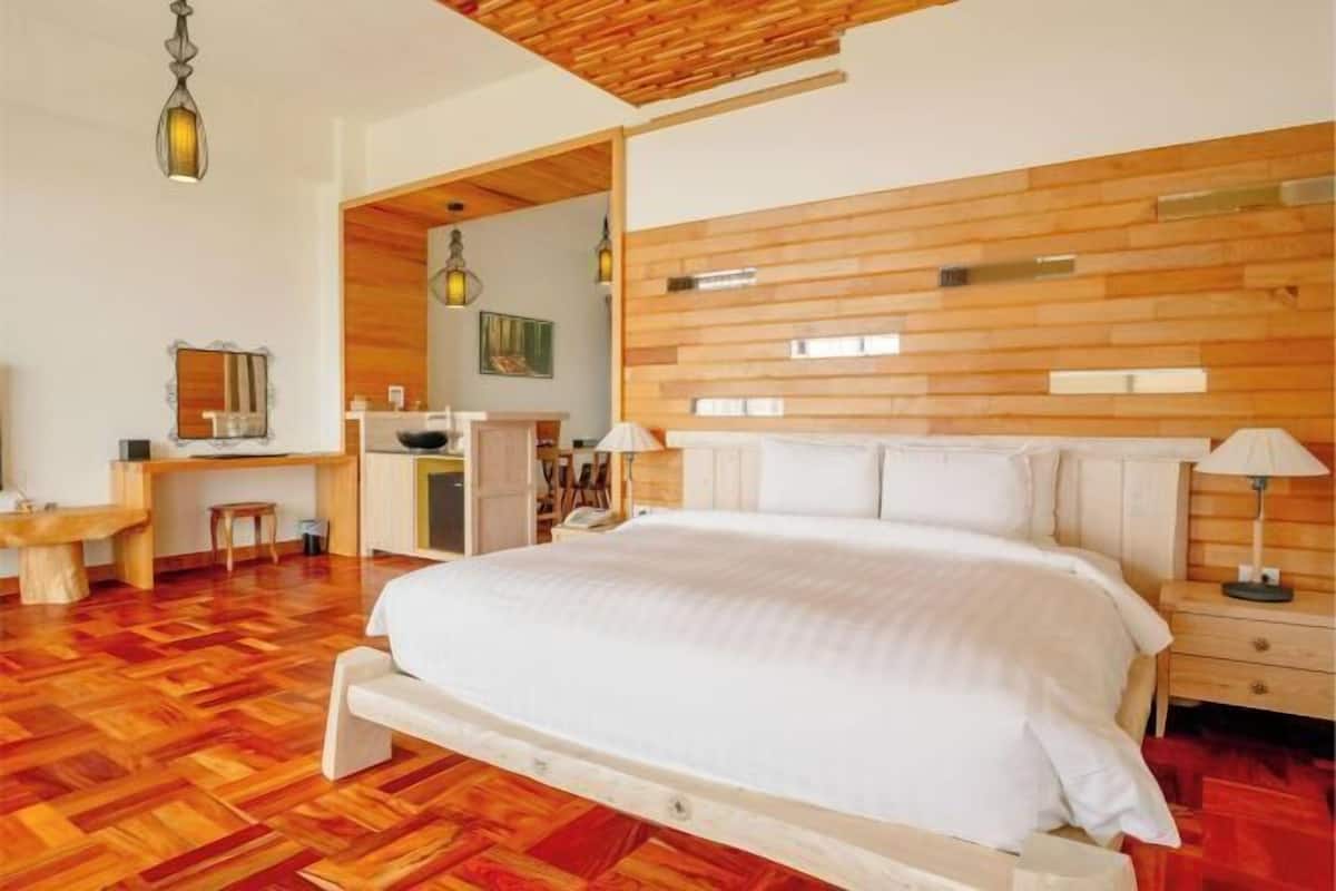 A bedroom with a wooden headboard, a bed, a desk, and a chair.