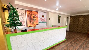 Ein Empfangstresen mit Grün-Weiß-Design, umgeben von Plakaten, darunter eines für das Restaurant 'The Byke Niranjana'.