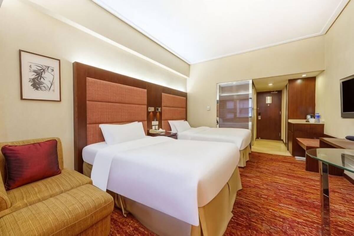 Een hotelkamer met twee bedden, een bank, een bureau en een televisie.