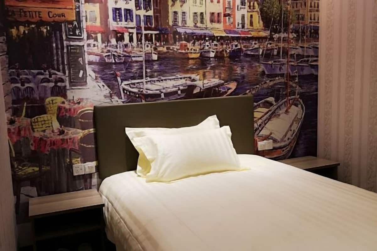 A hotel room with a bed, a nightstand, and a wall mural of a canal scene.