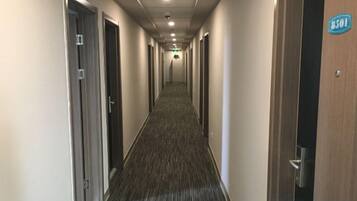 A hotel corridor with doors on both sides, a carpeted floor, and a sign indicating room number 8501.