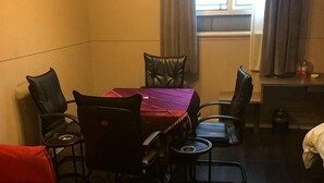 Ein Hotelzimmer mit Esstisch, Stühlen, einem roten Sofa und einem Fenster mit Vorhängen.