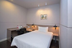 Habitación de hotel con cama, escritorio, silla y un cuadro en la pared.