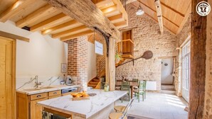 Una cocina rústica con una isla de mármol, vigas de madera y una pared de ladrillo.