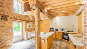 Una cocina rústica con paredes de piedra, vigas de madera y una isla grande.