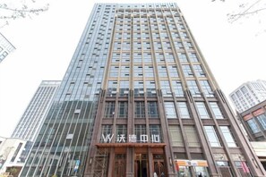 Een hoog, modern gebouw met een opvallende entree en grote ramen.