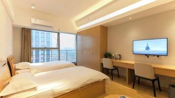 A hotel room with two beds, a desk, a chair, a TV, and a window with curtains.