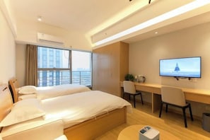 Ein Hotelzimmer mit zwei Betten, einem Schreibtisch, einem Stuhl, einem Fernseher und einem Fenster mit Vorhängen.