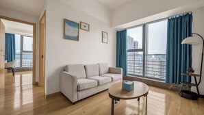 A modern living room with a sofa, a round table, and large windows with curtains. - Wuhan Boya Ward Hotel (Optics Valley Convention and Exhibition Center Joy City Branch) (Wuhan)