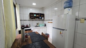 A compact kitchen with white tiled walls, a white refrigerator, a stove, and a sink. - Wicz Apart (Puerto Iguazú)