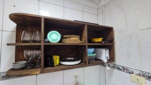 A wooden shelf unit with various kitchenware items, including plates, cups, and a toaster. - Wicz Apart (Puerto Iguazú)