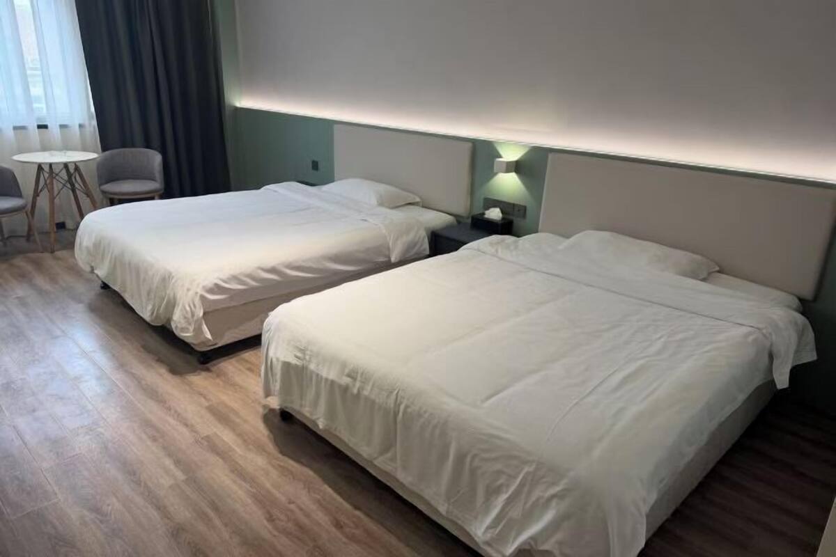Ein Hotelzimmer mit zwei Betten, einem kleinen Tisch und einem Stuhl.