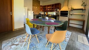A dining area with a round table, colorful chairs, and a patterned rug. - Moçamba LODGE Contêiner (Florianópolis)