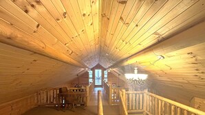 Un interno in legno con soffitto alto, una scala e una vista attraverso una finestra.