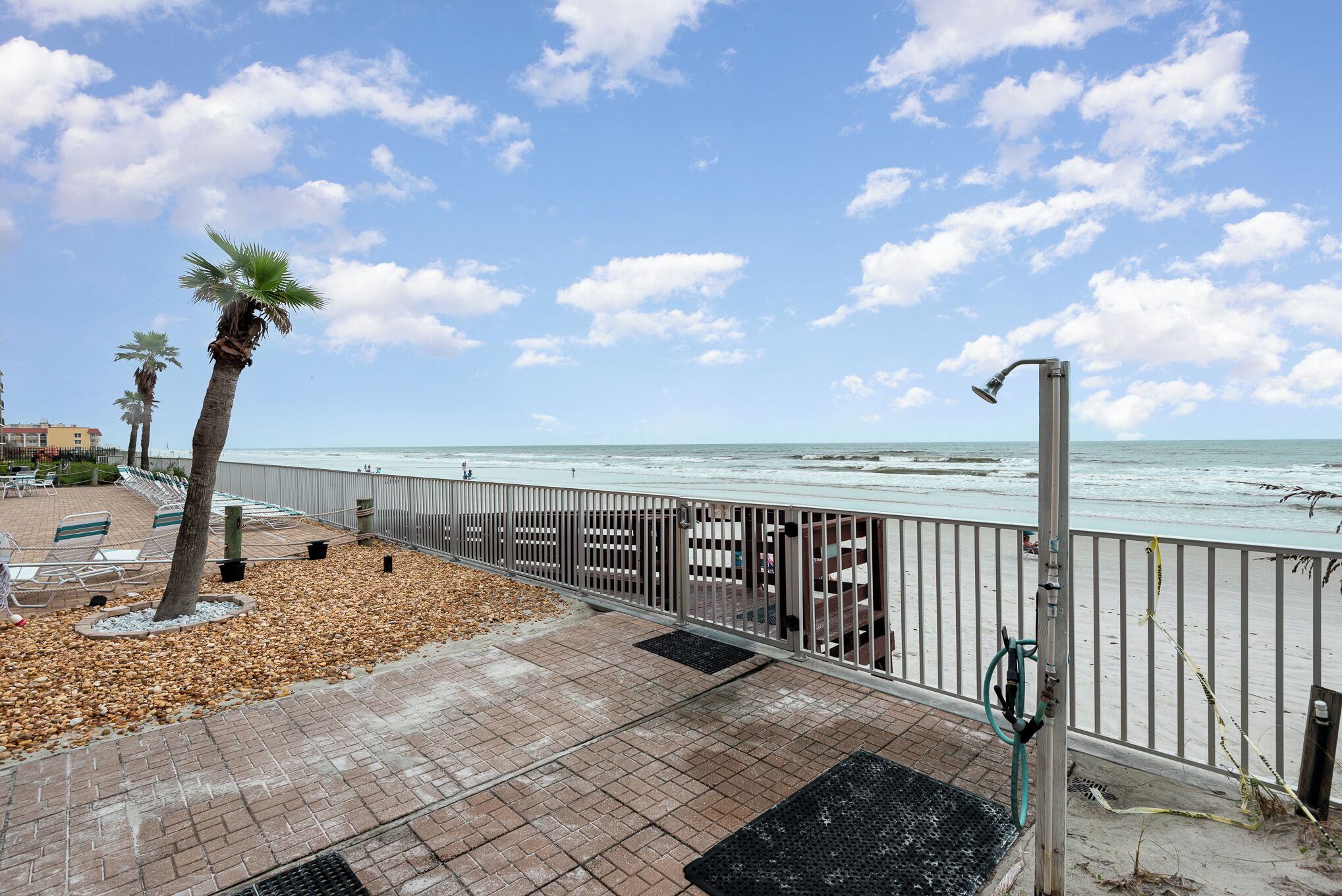 Une promenade en bord de mer, bordée de palmiers, agrémentée de bancs et dotée d’une rambarde métallique d’où l’on peut admirer l’océan.