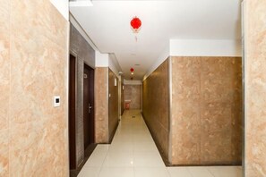 Un corridoio con pareti, porte e un ornamento rosso appeso in marmo.