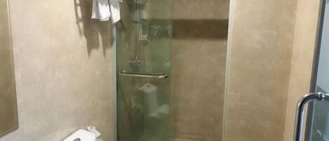 A glass-enclosed shower stall with a toilet and a towel rack.