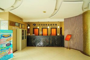 A hotel reception area with a reception desk, a wall-mounted sign, and a poster on the left. - Yiyezhou Business Chain Hotel (Changzhou)