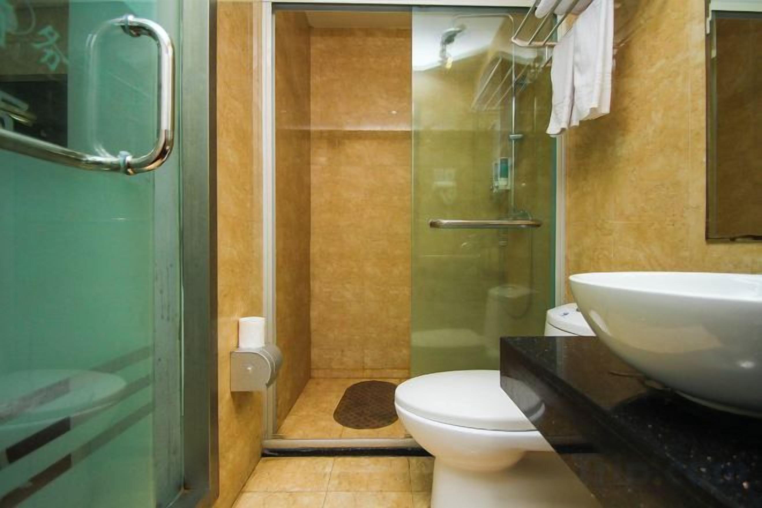 Ein Badezimmer mit einer Duschkabine aus Glas, einer weißen Toilette und einem großen Waschbecken.