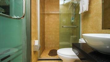 A bathroom with a glass shower enclosure, a white toilet, and a large sink.