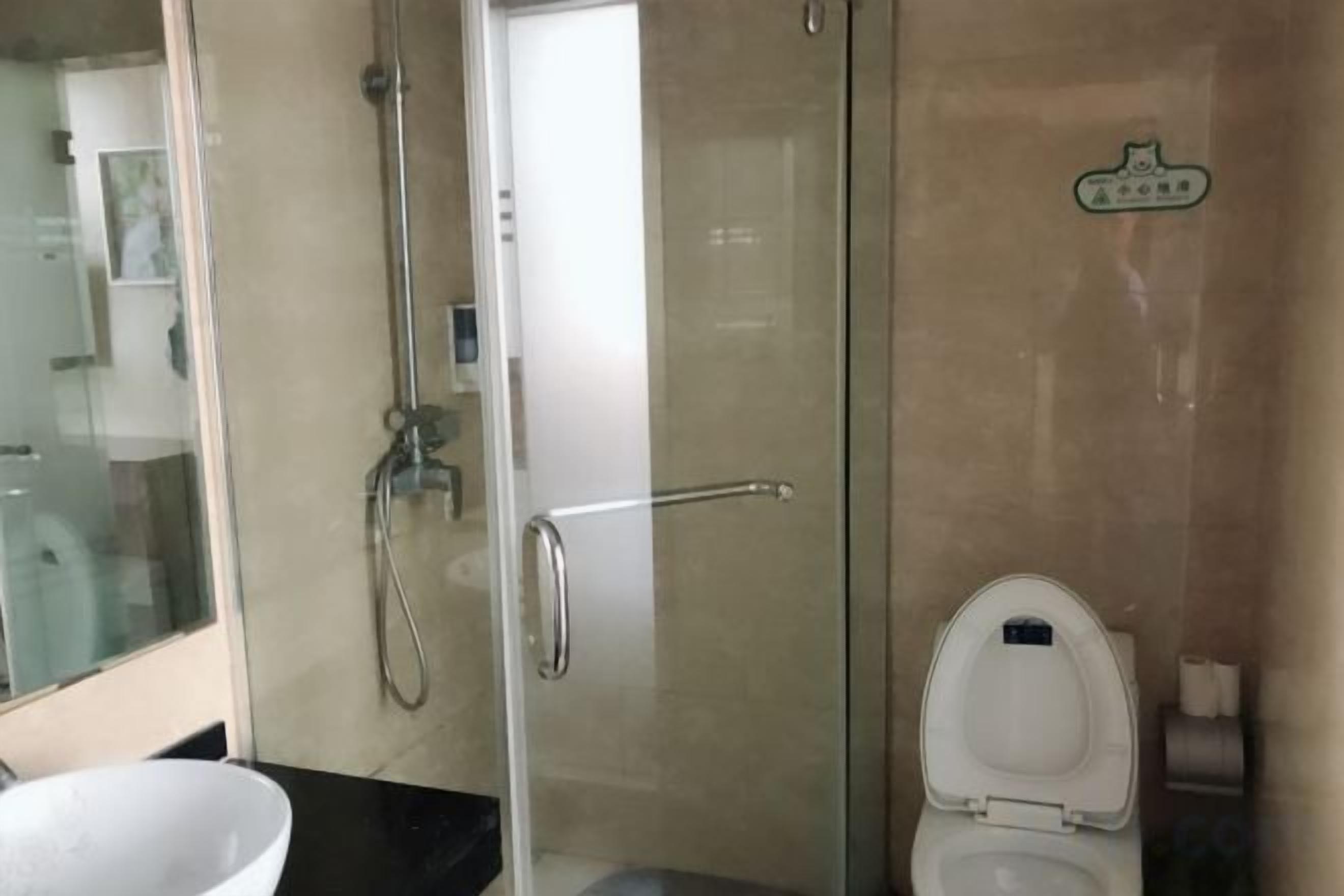 Ein Badezimmer mit Duschkabine aus Glas, Toilette und Waschbecken.