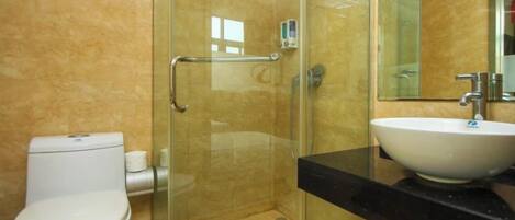 A bathroom with a glass-enclosed shower, a white toilet, and a sink with a black countertop.