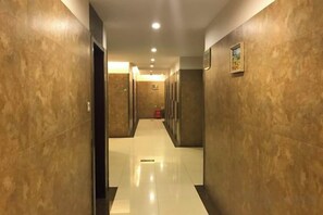 A hotel hallway with a polished floor, doors on both sides, and a fire extinguisher on the right. - Yiyezhou Business Chain Hotel (Changzhou)