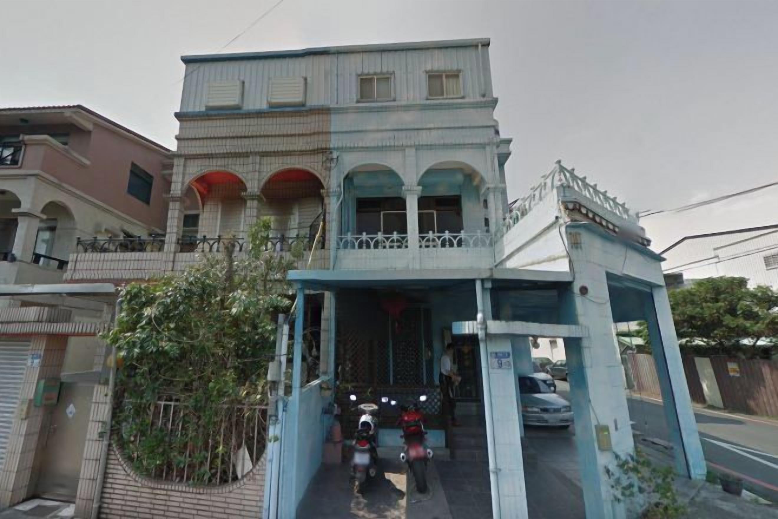 A two-story building with a covered entrance and a balcony.