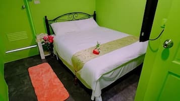 A room with a bed, a nightstand with a lamp, and a small orange rug.