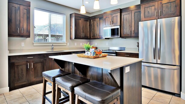 A modern kitchen with dark wood cabinets, stainless steel appliances, and pendant lighting. - Entrada at Moab 619 (Moab)
