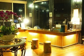 A reception desk with a computer, a telephone, and a lamp. There is a potted plant on a table to the left. - Chingjing Top Cloud Resort (Nantou)