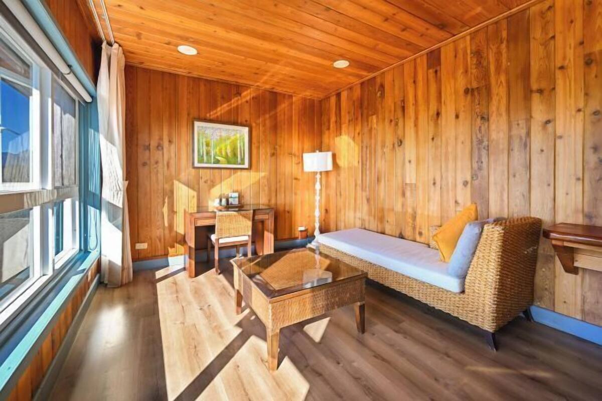 A cozy room with wooden walls, a sofa, a table, and a lamp.