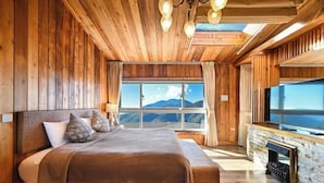 A wooden room with a large bed, a TV, and a stone fireplace. - Chingjing Top Cloud Resort (Nantou)