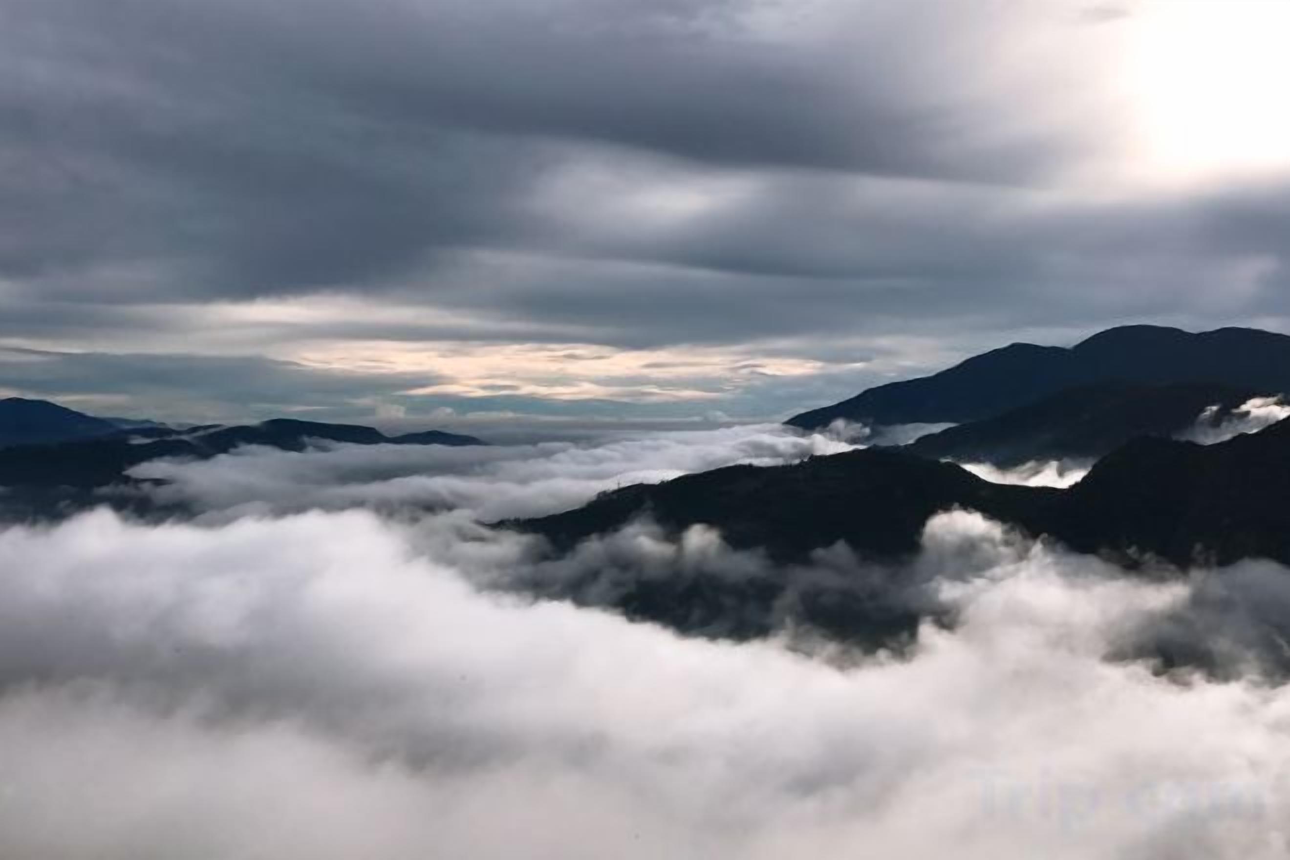 Un paysage montagneux, avec un ciel nuageux et des pics montagneux lointains.