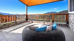 A covered balcony with a wicker sofa, stone walls, and a view of mountains. - Chingjing Top Cloud Resort (Nantou)