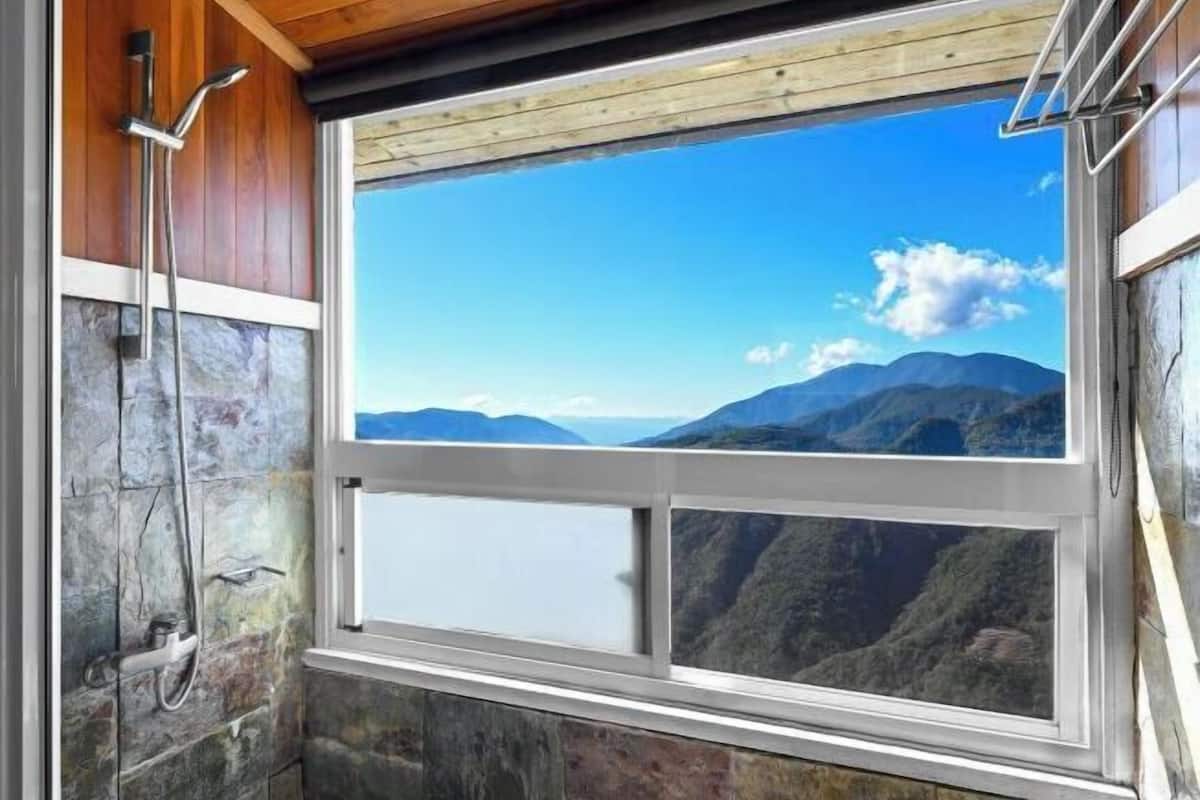 A bathroom with a large window offering a mountain view.