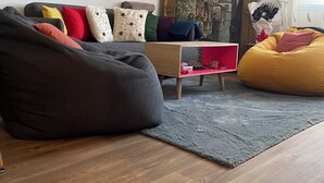 A living room with a grey sofa, colorful cushions, a black bean bag, a small wooden table, and a framed painting on the wall. - Cosy host apartment (Bir El Djir)