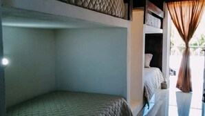 Een kamer met stapelbedden, een plafondlamp en een raam met gordijnen.