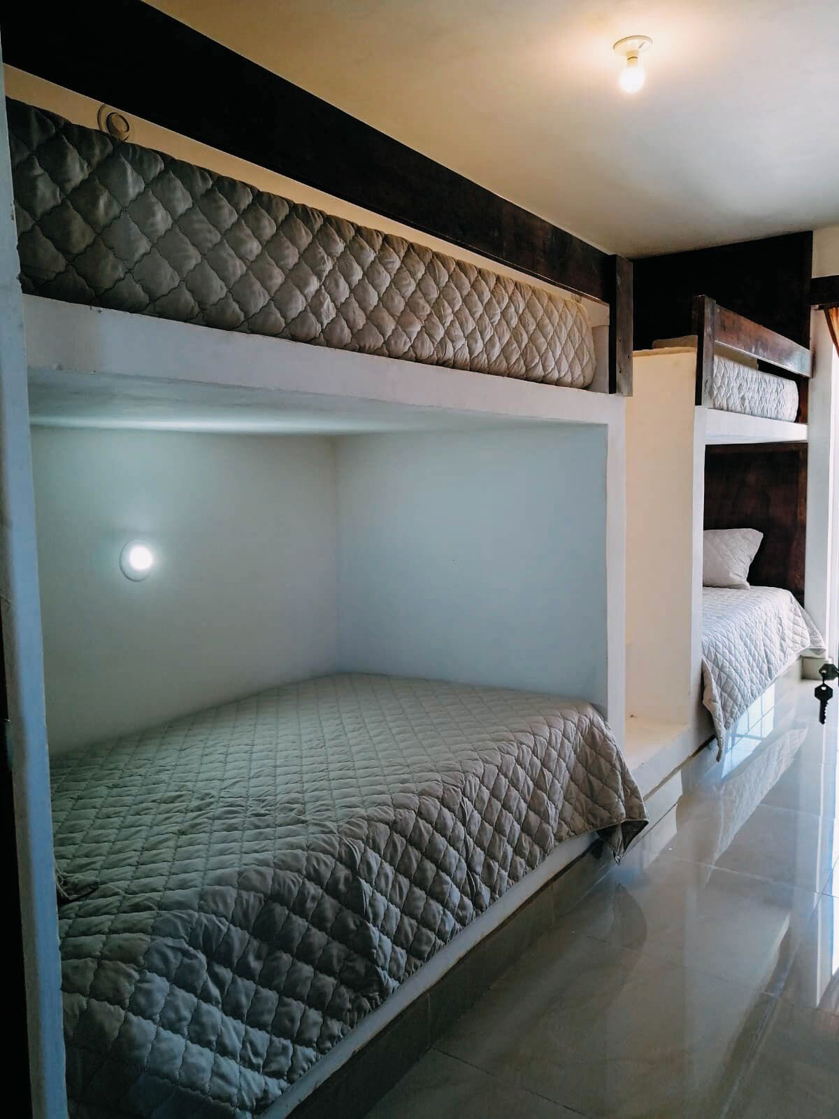 A bunk bed with a quilted mattress and a headboard with a textured pattern.