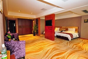 A hotel room with a large bed, a TV, a sofa, and a decorative plant. - Hirsman Guangzhou (Guangzhou North Railway Station) (Guangzhou)