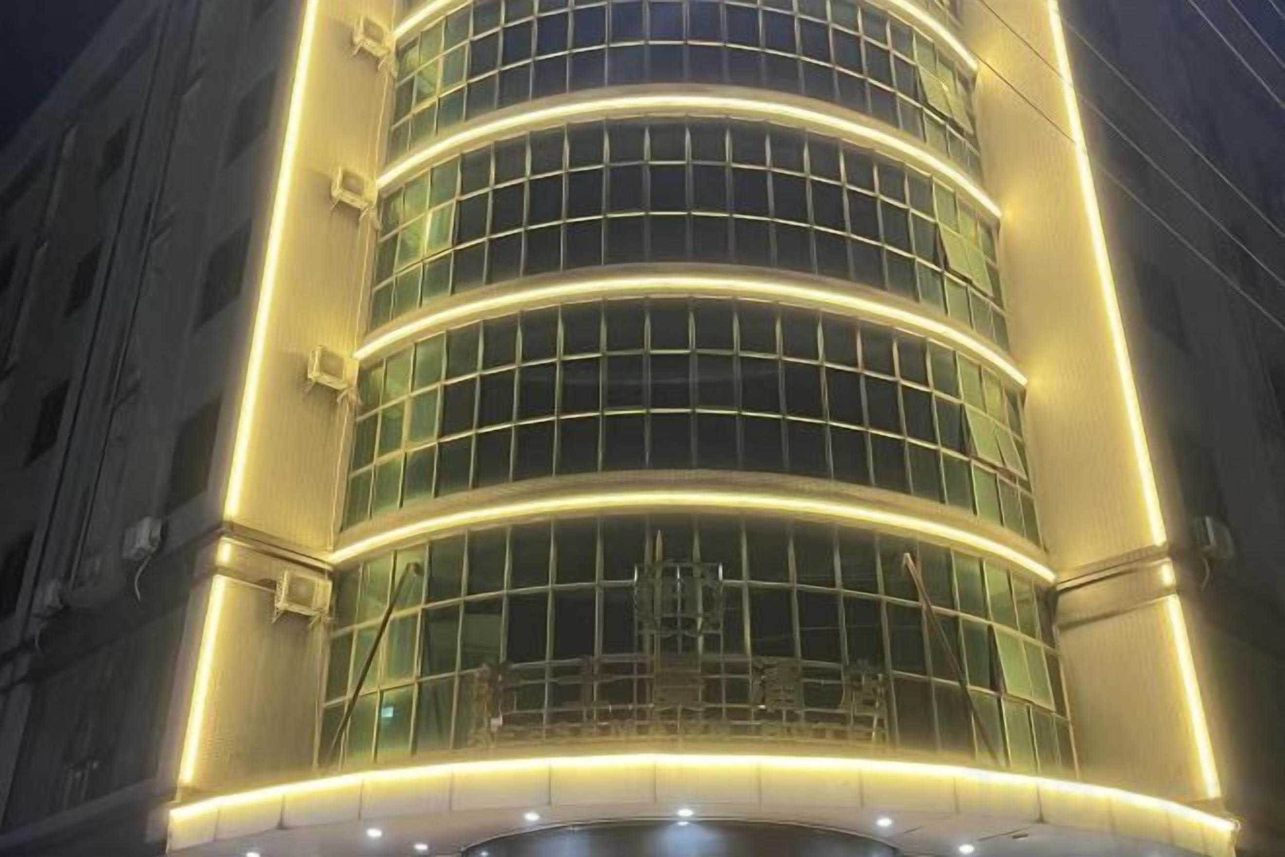 Een meerhoog gebouw met een gebogen gevel en verlichte ramen.